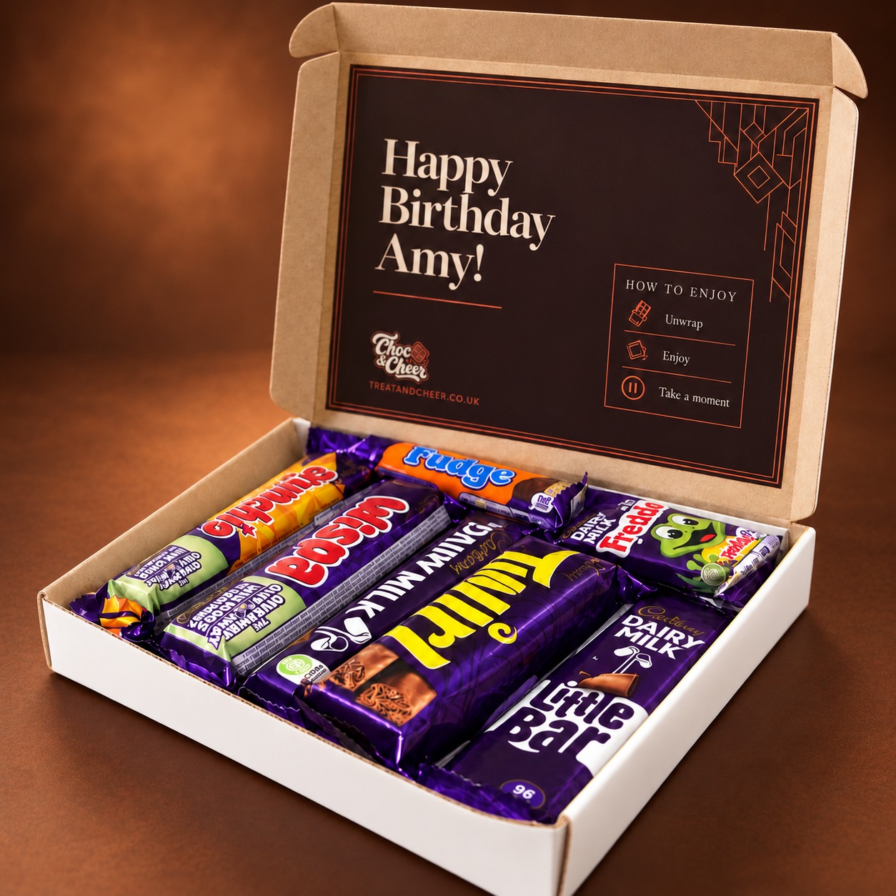 White chocolate gift box with a brown inside lid and birthday message, filled with wrapped Cadbury chocolates